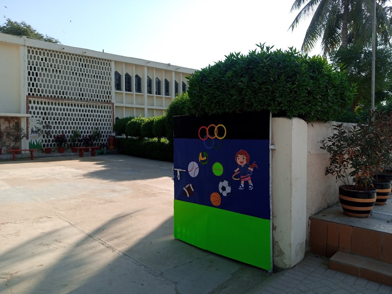 School courtyard with a sports mural and palm trees at an Aga Khan School campus