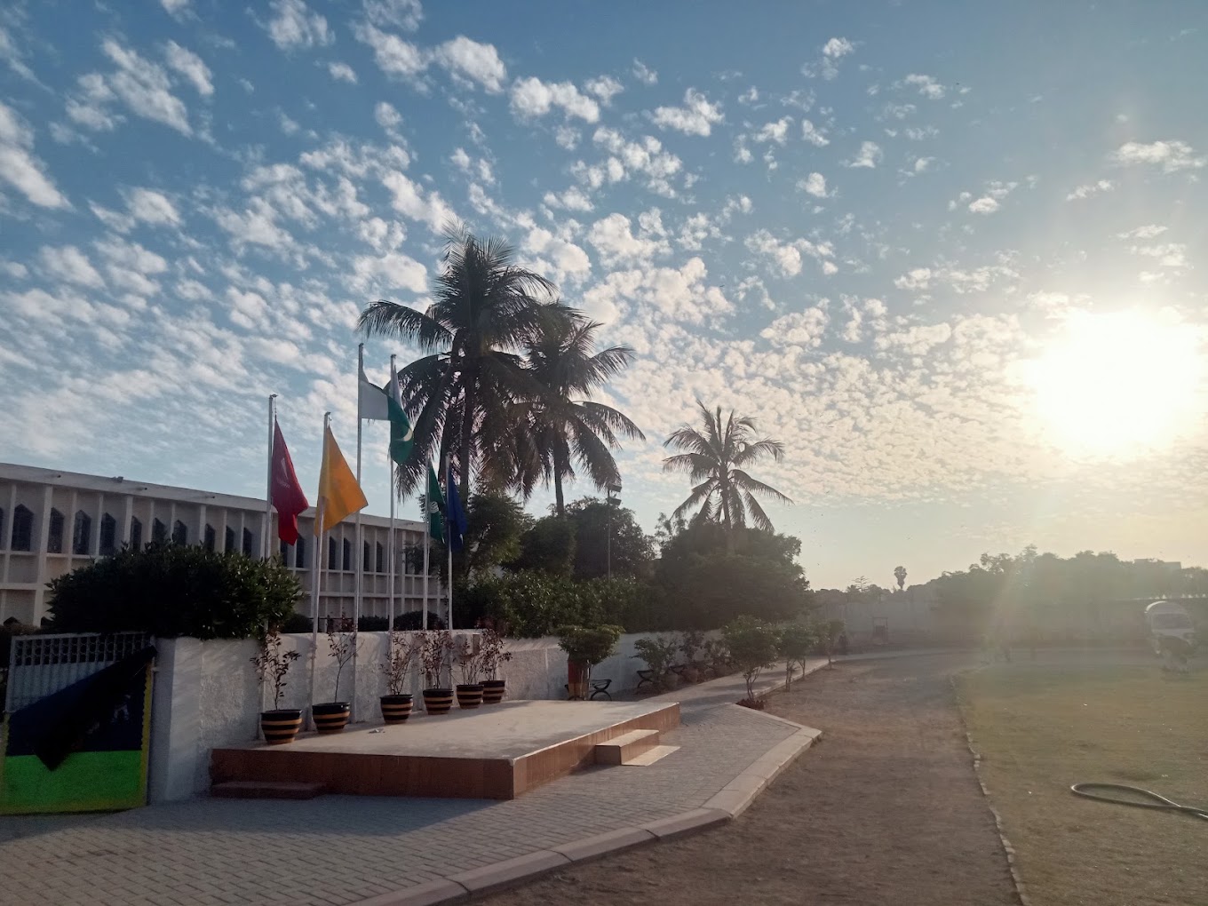 Flags flying at sunrise beside the palm-lined grounds of the Aga Khan School, Garden, Karachi